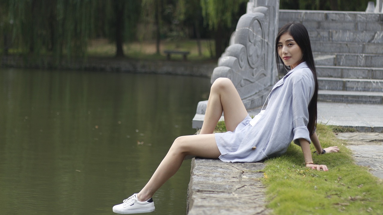 a woman sitting on a ledge next to a body of water, a picture, inspired by Ma Yuanyu, tumblr, white soft leather model, in a city park, wearing a towel, yintion j - jiang geping