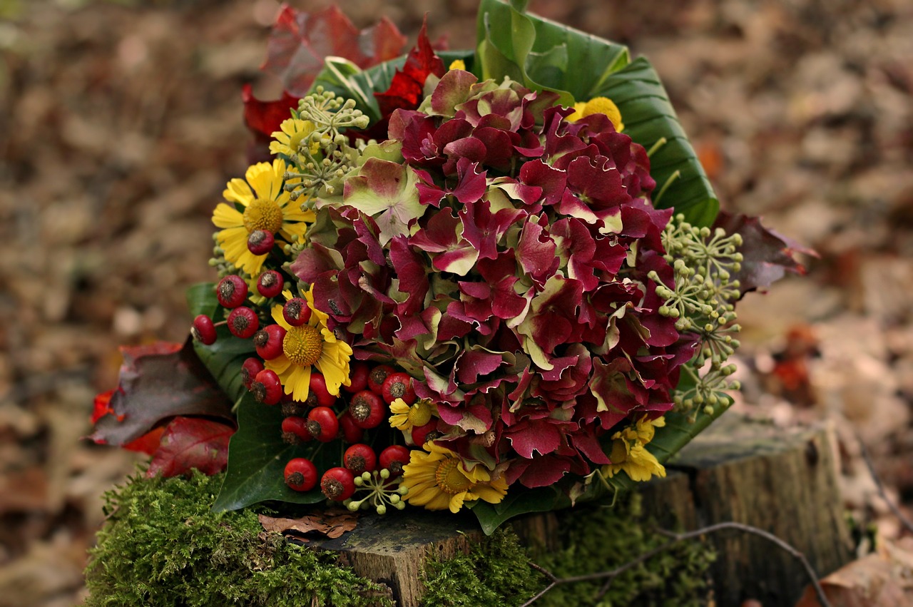 a bouquet of flowers sitting on top of a tree stump, by Maksimilijan Vanka, pixabay, red and yellow color scheme, hydrangea, autumnal, h.r. geiger