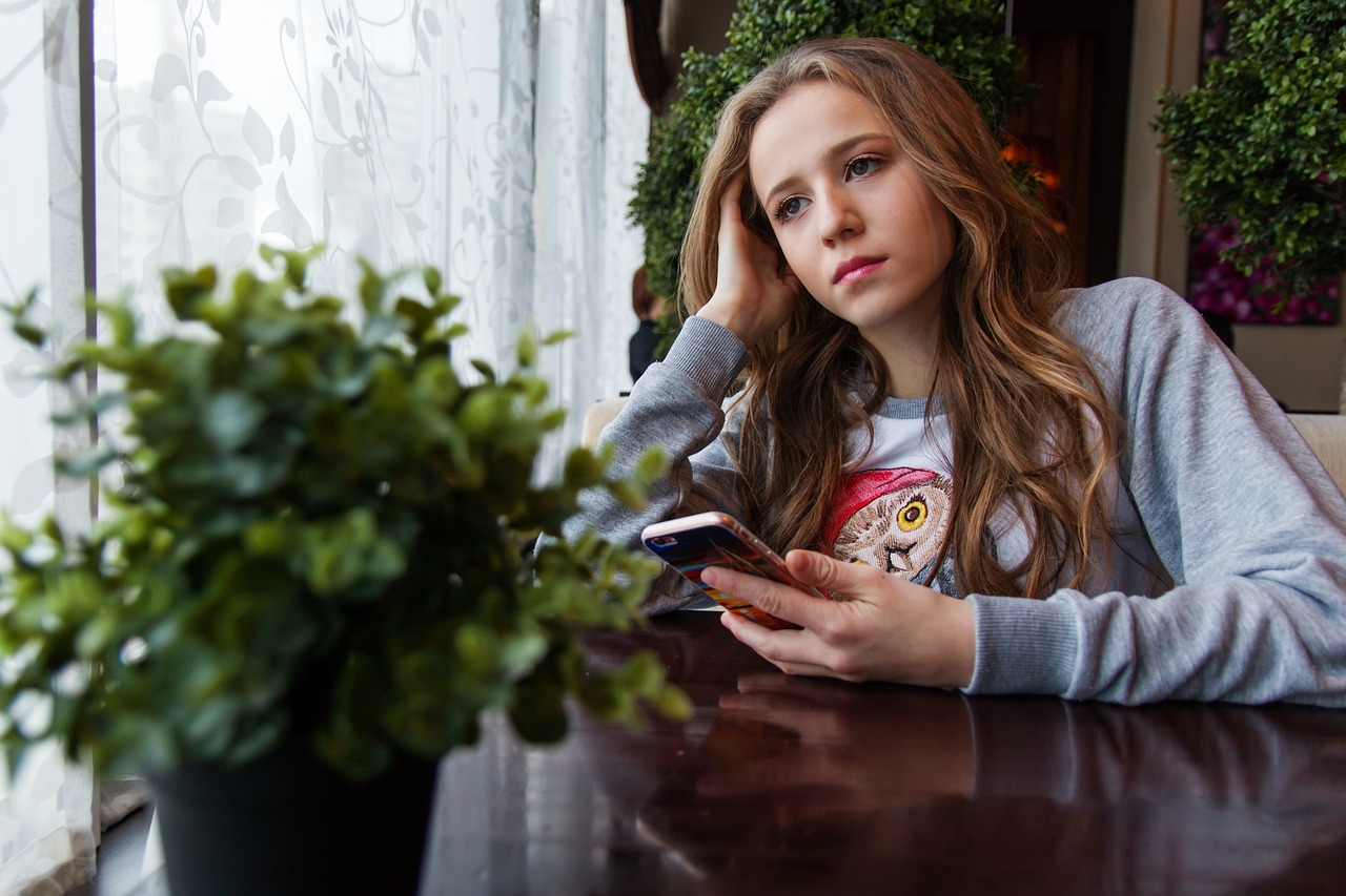 a woman sitting at a table looking at her cell phone, happening, beautiful taissa farmiga, portrait of depressed teen, ukrainian girl, a beautiful teen-aged girl