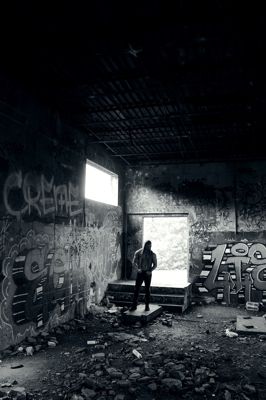 a person standing in a room with graffiti on the walls, a black and white photo, inspired by Gregory Crewdson, flickr, graffiti, graffiti in an abandoned bunker, rap scene, back - lit, ((oversaturated))
