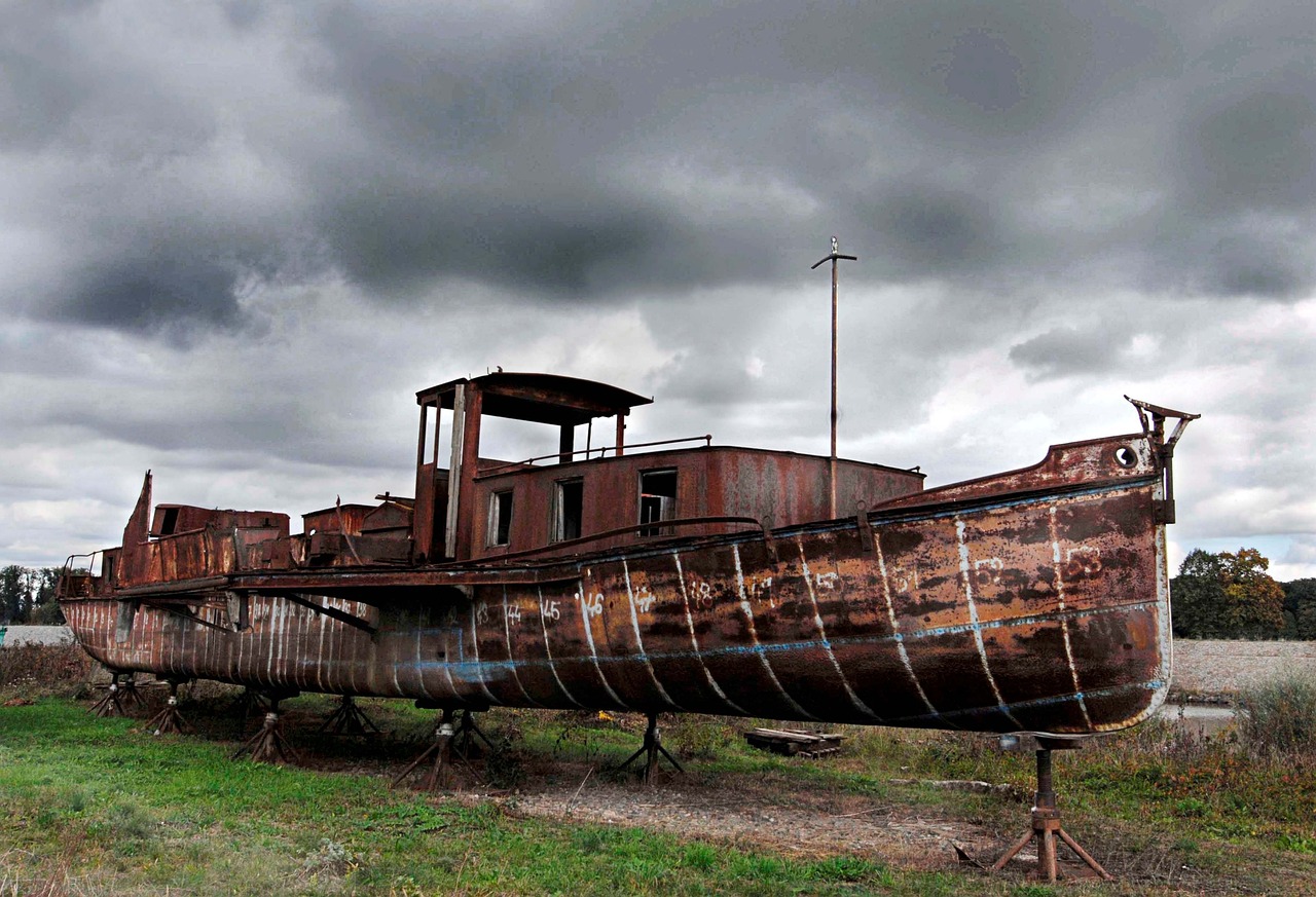 a rusty boat sitting on top of a grass covered field, by Arthur Sarkissian, flickr, under a dark cloudy sky, zeppelin dock, dieselpunk volgograd, amazing beauty