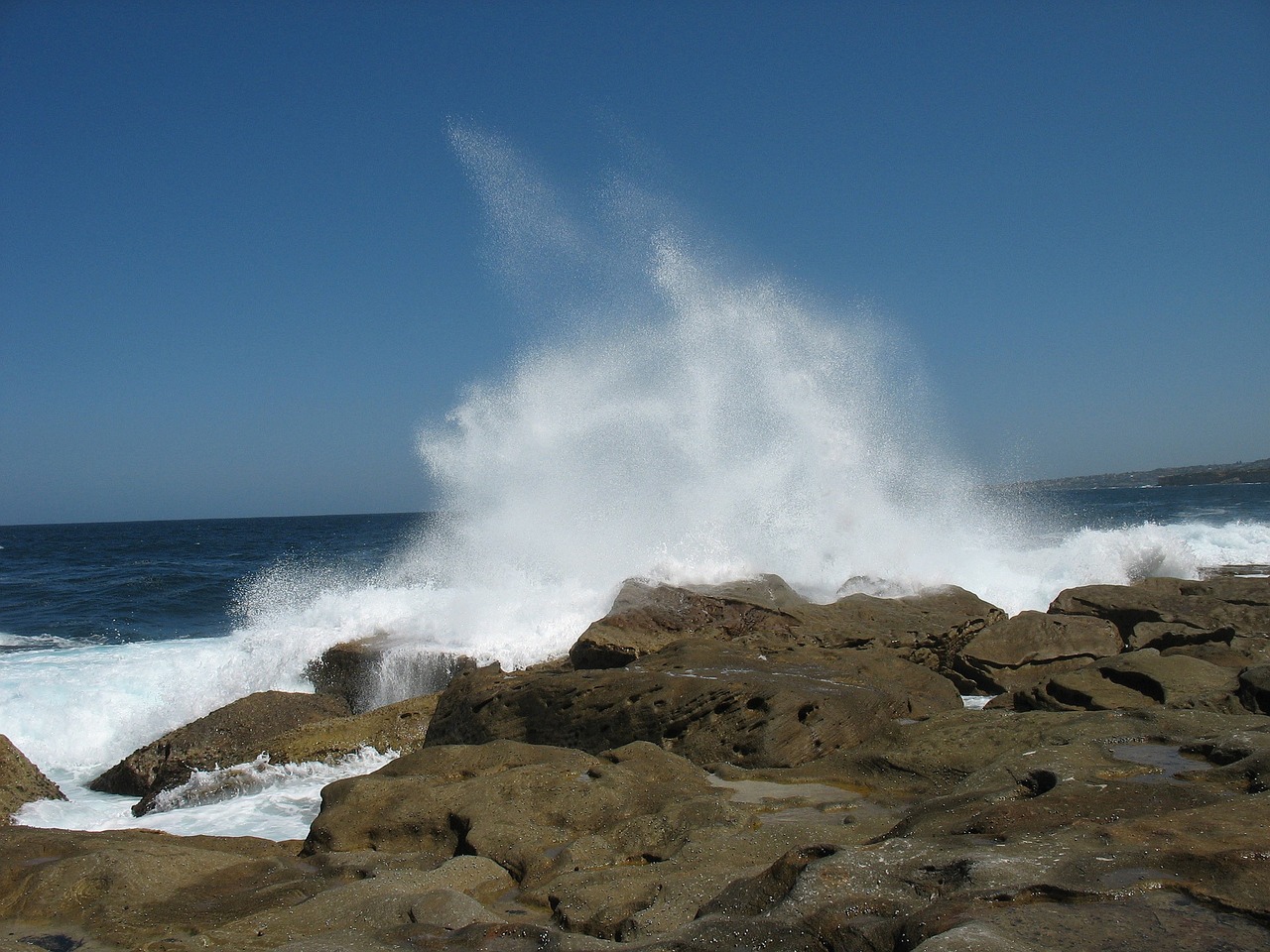 a person riding a surfboard on top of a rocky beach, a picture, by Elizabeth Durack, extremely strong wind, big splash, tourist photo, shot on a 2 0 0 3 camera