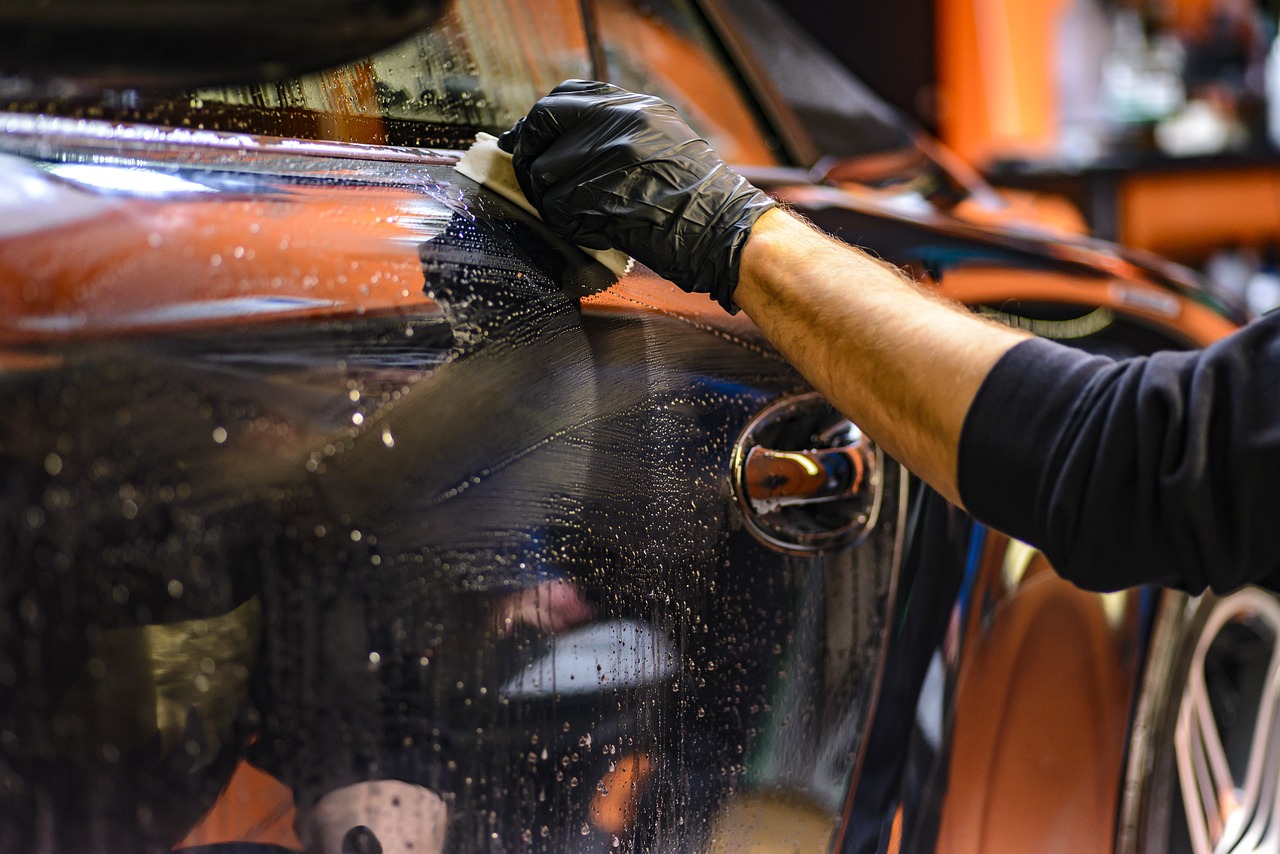 a man waxing a car with a sponge, a picture, shutterstock, black car, photo taken in 2 0 2 0, manicured, wearing gloves