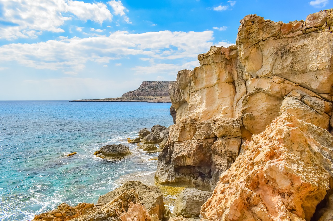 a man standing on top of a cliff next to the ocean, a photo, by Edward Corbett, shutterstock, cyprus, rocky beach, high detail photo of a deserted, brown