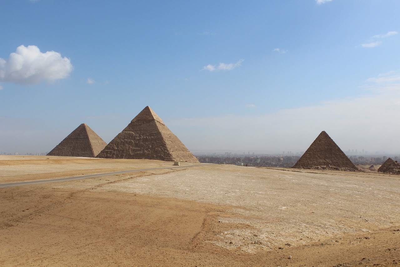 a group of three pyramids sitting on top of a desert, egyptian art, pexels, plein air, panorama of crooked ancient city, photo taken in 2018, blue sky, ancient megastructure pyramid