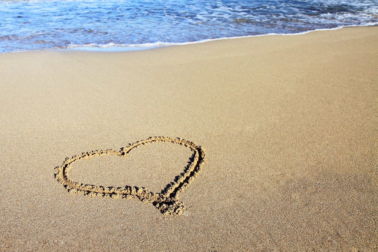 a heart drawn in the sand on a beach, romanticism, high res, vacation photo