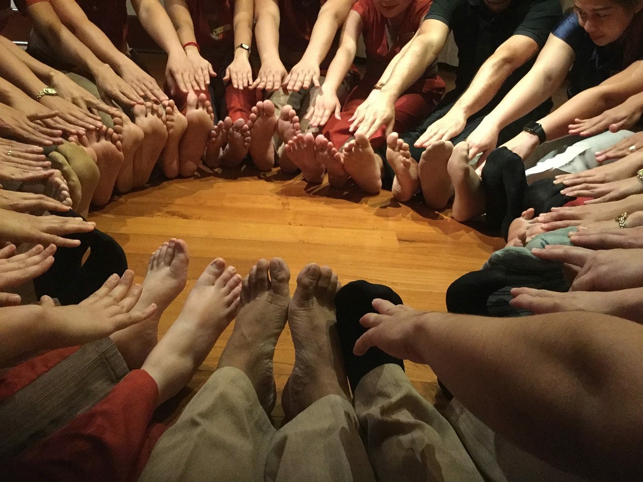 a group of people holding their hands in a circle, a picture, by Nina Hamnett, feet posing, sacred, indoor, reds