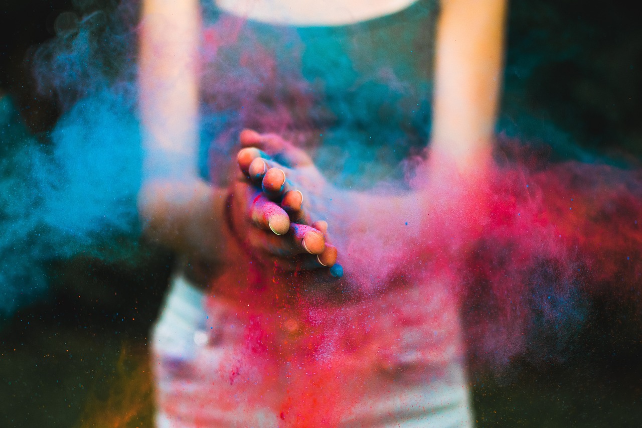 a person with colored powder on their hands, a colorized photo, blur dreamy outdoor, vibrant deep saturated colors, thick dust and red tones, with colourful intricate