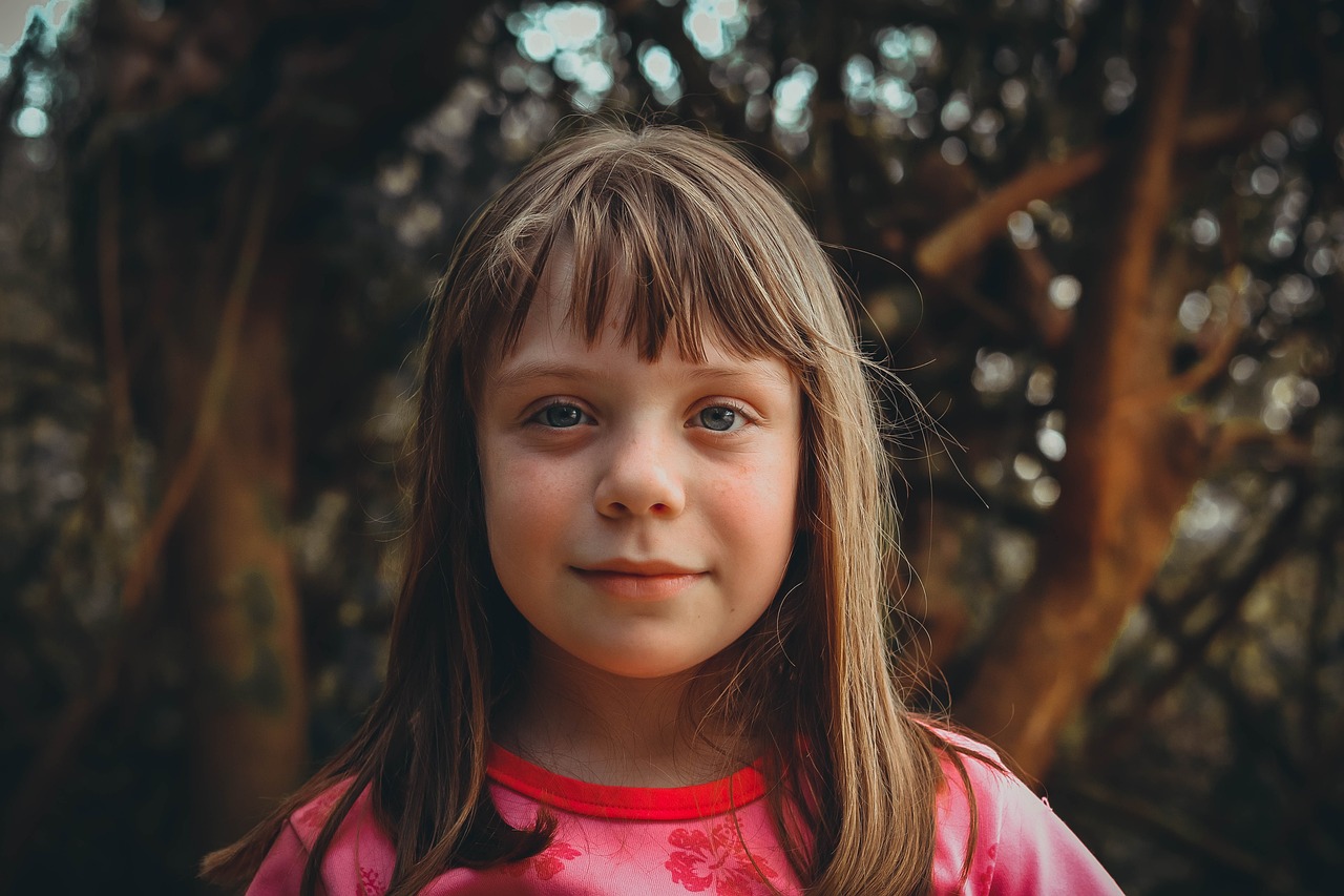 a little girl standing in front of a tree, by Matt Cavotta, pexels contest winner, realism, center parted bangs, glowing pink face, greta thunberg smiling, portrait of a beautiful girl