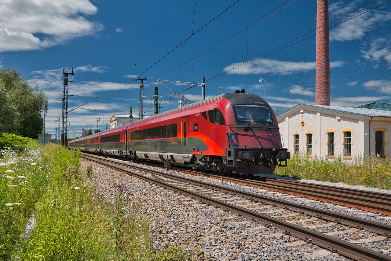 a large long red train on a steel track, by Karl Völker, shutterstock, train station in summer, left profile, training, stock photo