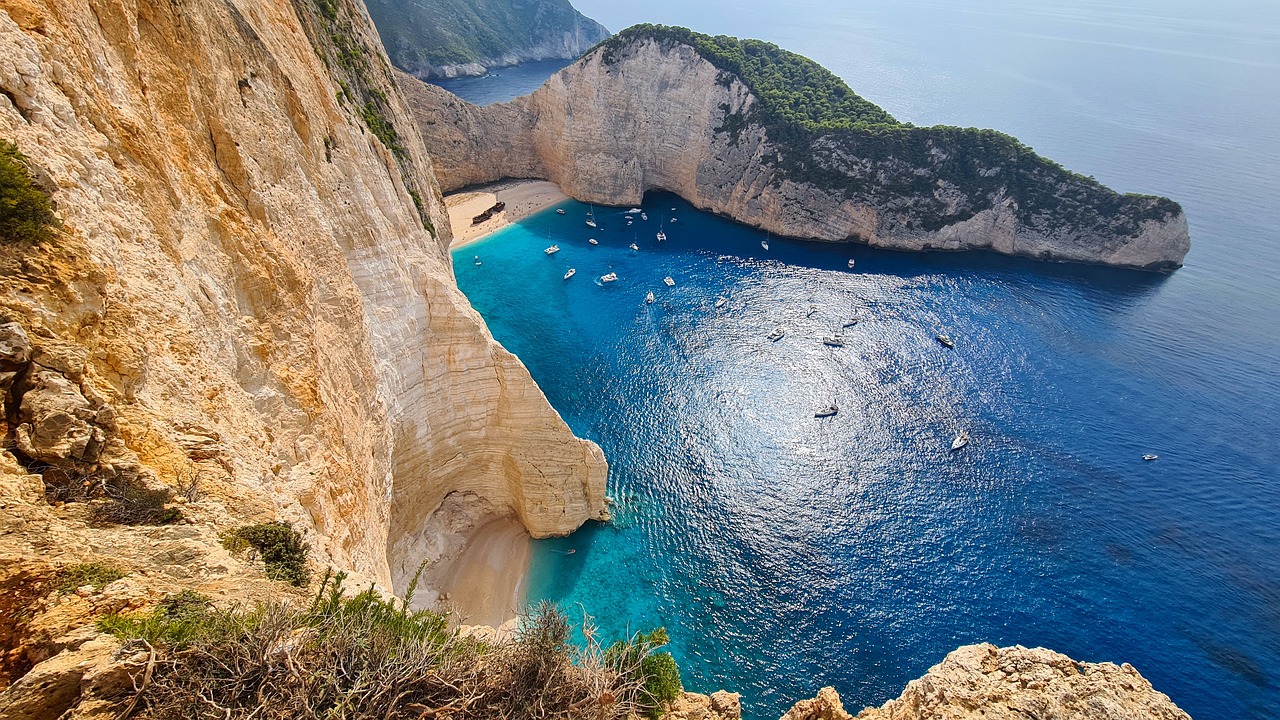 a large body of water next to a cliff, a picture, by Alexis Grimou, greek nose, beautiful beach, with water and boats, jaw dropping