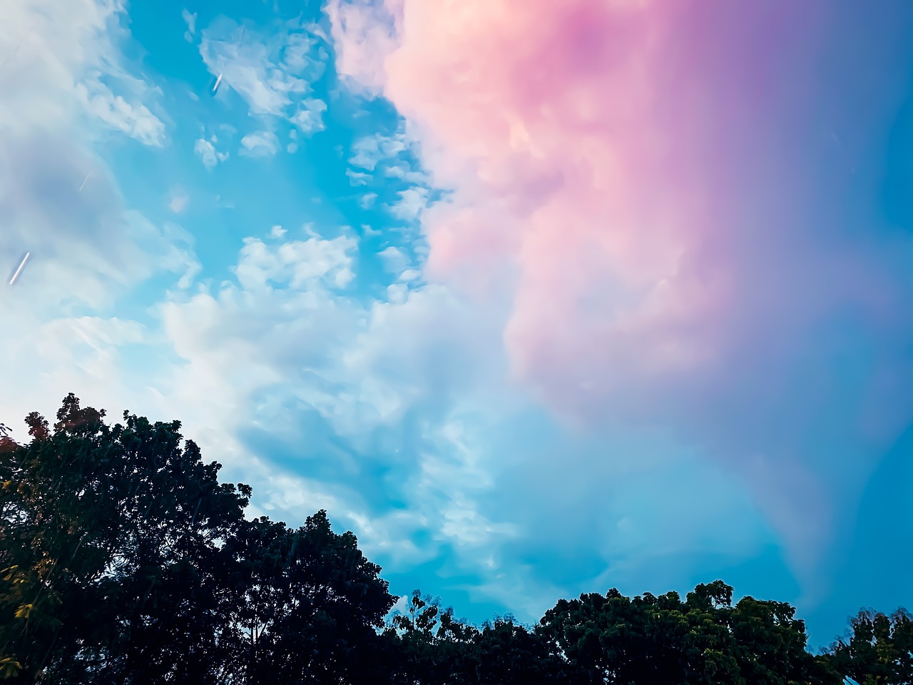 there is a plane that is flying in the sky, inspired by Maxfield Parrish, aestheticism, (((colorful clouds))), blue and pink colour splash, over the tree tops, shot with premium dslr camera
