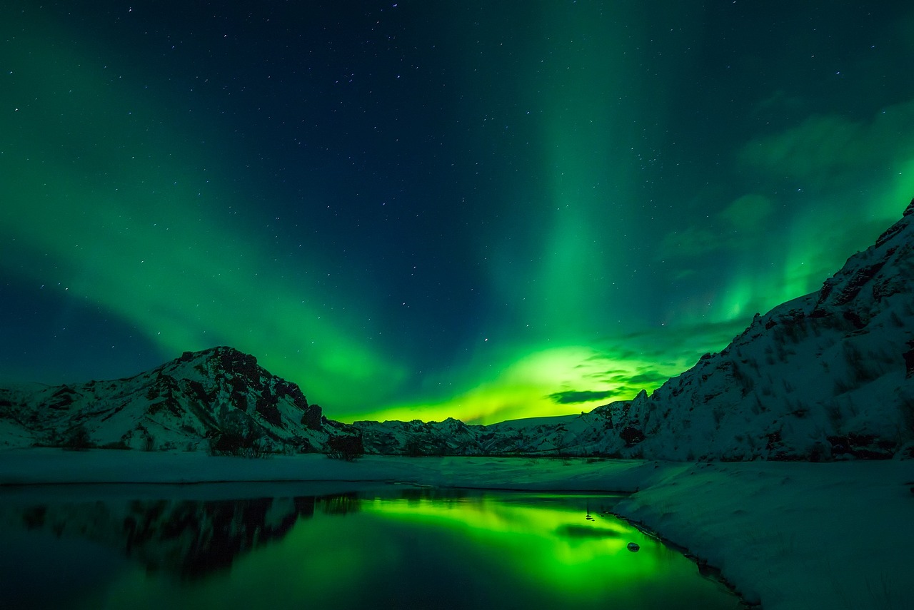 a large body of water surrounded by snow covered mountains, a picture, by Alexander Bogen, pexels, glowing green lights, an icelandic landscape, marvellous reflection of the sky, inside an epic