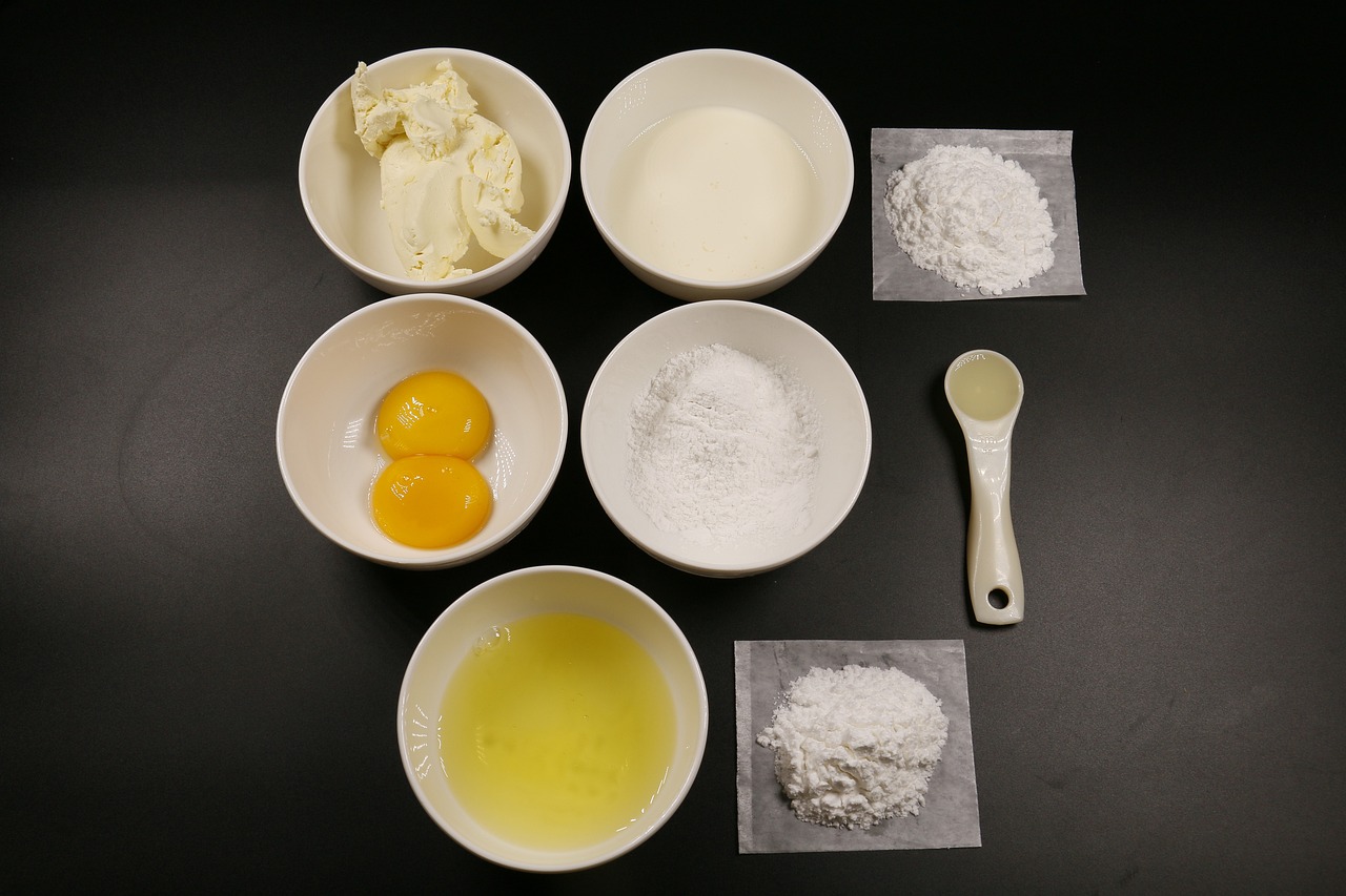 a table topped with bowls of food next to a spoon, powdered sugar, product introduction photo, egg, butter