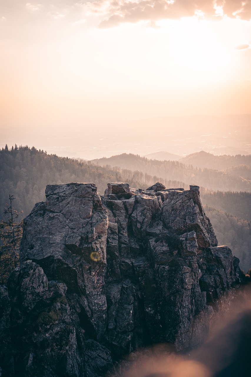 a person standing on top of a large rock, a tilt shift photo, romanticism, black forest, early morning sunrise, rock roof, shot from far away