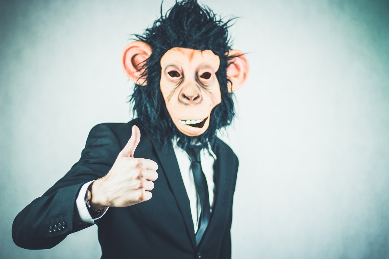 a man wearing a monkey mask giving a thumbs up, a stock photo, by Emma Andijewska, shutterstock, in a business suit, chimpanzee, using dead lion costume jacket, close up portrait photo