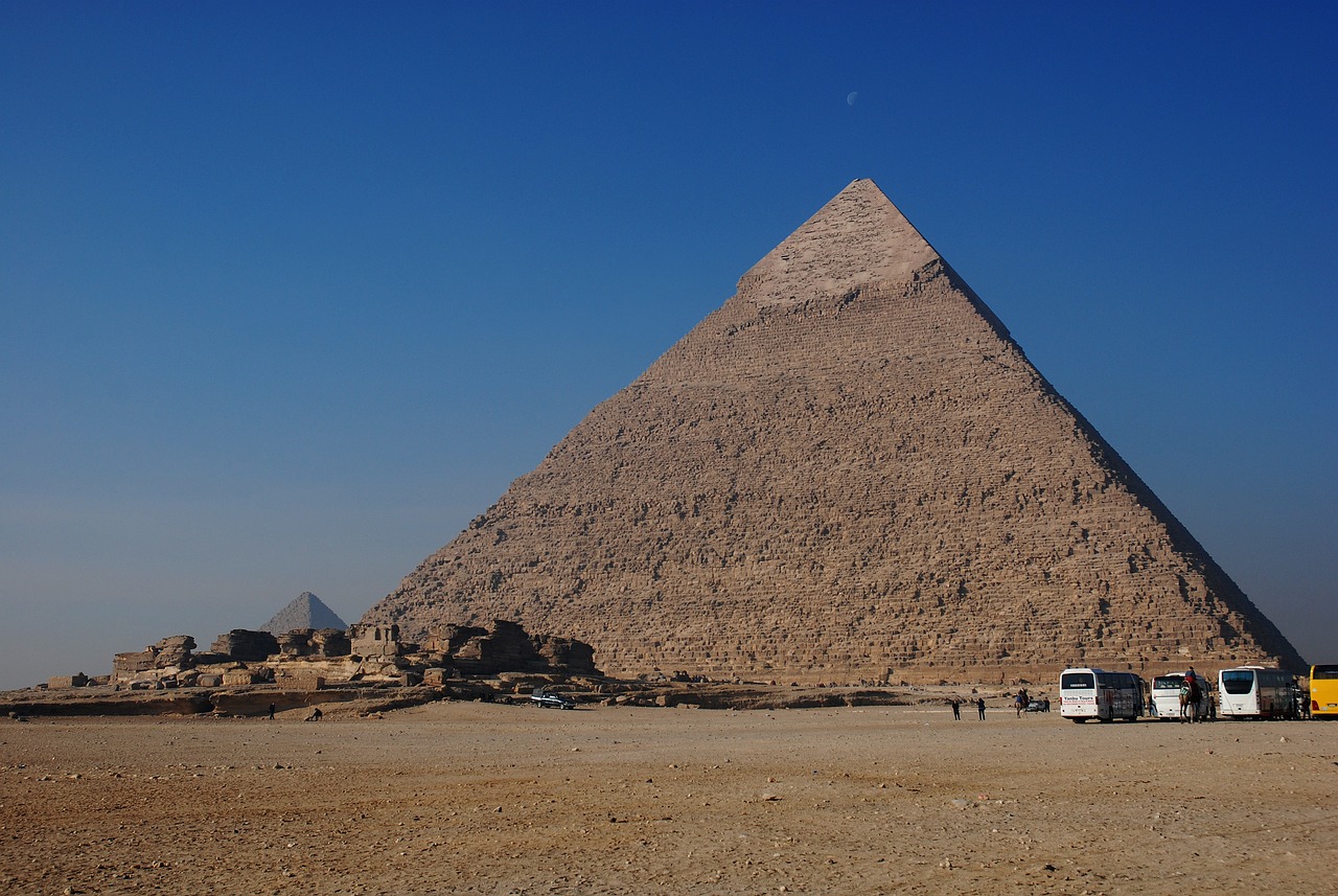 a truck is parked in front of a pyramid, egyptian art, by Robert Zünd, flickr, big moon on the right, huge gargantuan scale, winter sun, lost world pyramid