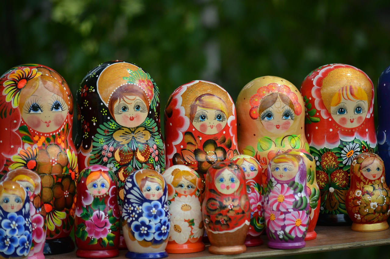 a row of matry dolls sitting on top of a wooden table, a picture, by Serhii Vasylkivsky, trending on pixabay, decorated with russian motifs, summer setting, stacked image, kaleidoscopic