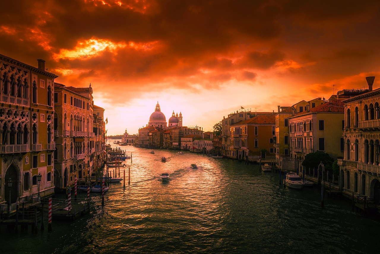 a river running through a city next to tall buildings, a photo, by Alessandro Allori, shutterstock, baroque, red stormy sky, venice, rays of golden red sunlight, stock photo
