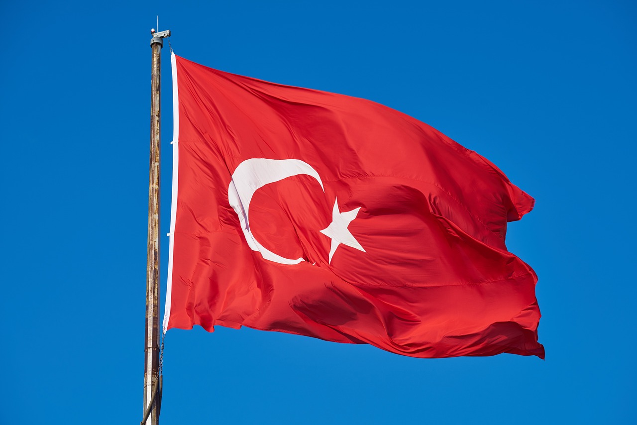 a turkish flag blowing in the wind against a blue sky, a picture, by Nevin Çokay, shutterstock, very detailed picture, red background, one eye red, hyperdetailed