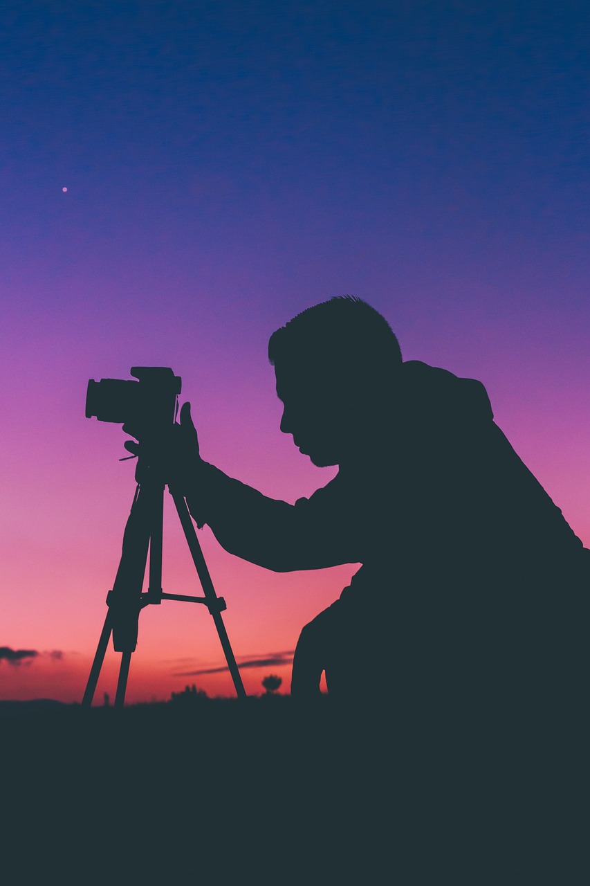 a silhouette of a man with a camera on a tripod, a picture, pexels contest winner, art photography, stock photo, night time footage, sunset lighting 8k, over-the-shoulder-shot