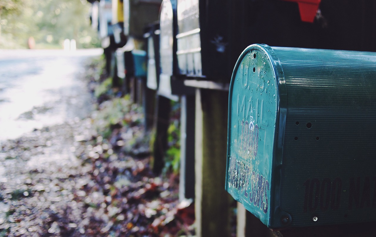 a row of mail boxes sitting on the side of a road, a photo, unsplash, mail art, teals, cinematic close shot, cozy, kiss