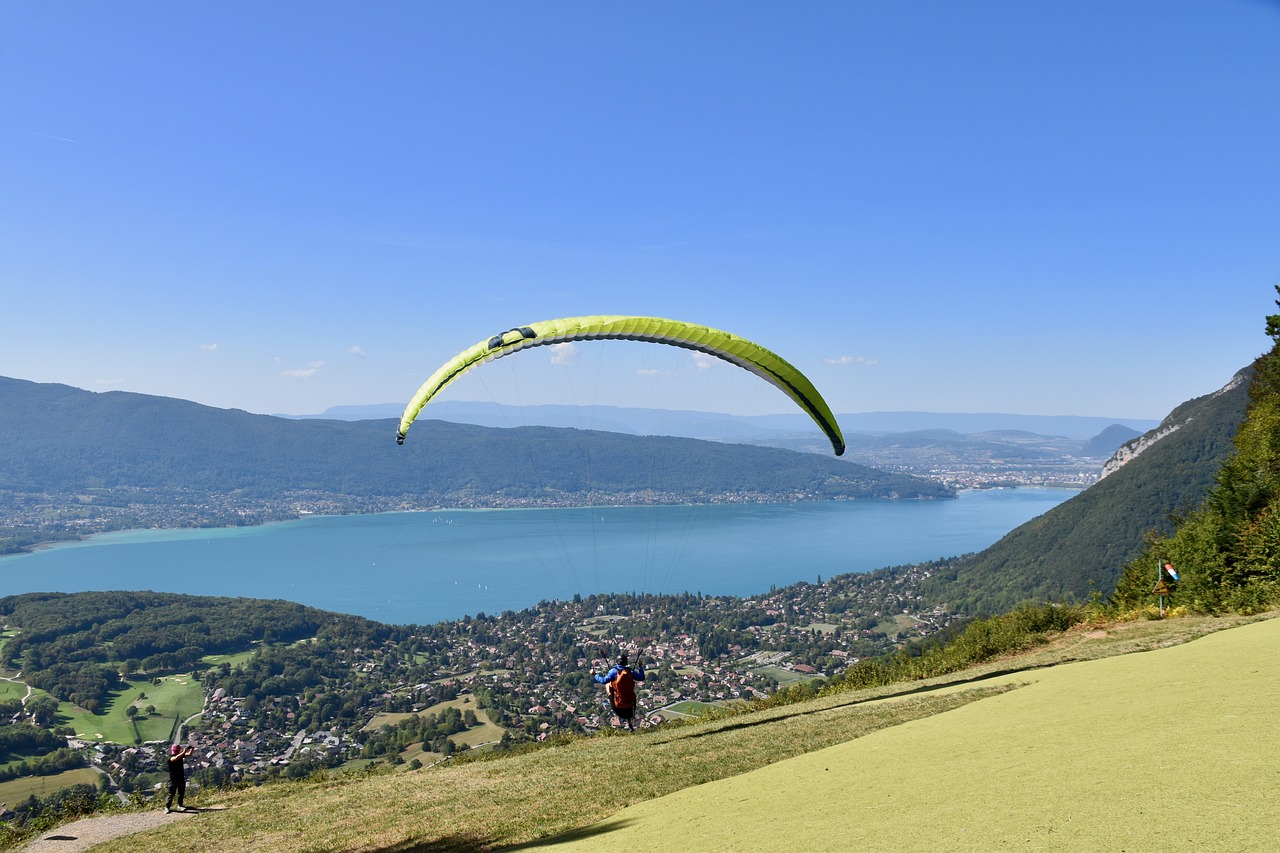 a group of people standing on top of a lush green hillside, a picture, by Cedric Peyravernay, shutterstock, soaring over a lake in forest, gliding, brochure, view from the side