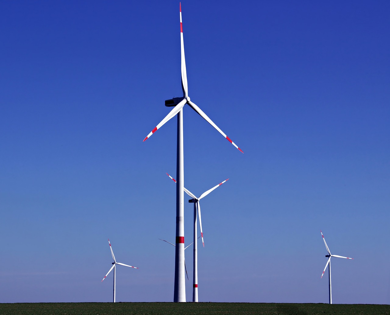 a group of wind turbines sitting on top of a green field, bauhaus, blue clear skies, ƒ/2.5, monitor, mines