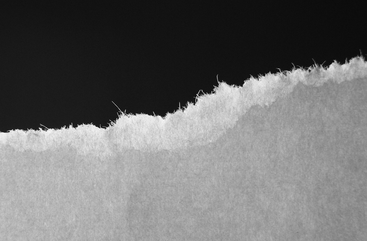 a man riding a snowboard down a snow covered slope, a black and white photo, inspired by Arnold Newman, unsplash, postminimalism, close up of single sugar crystal, old weathered paper, black backround. inkscape, made of paper