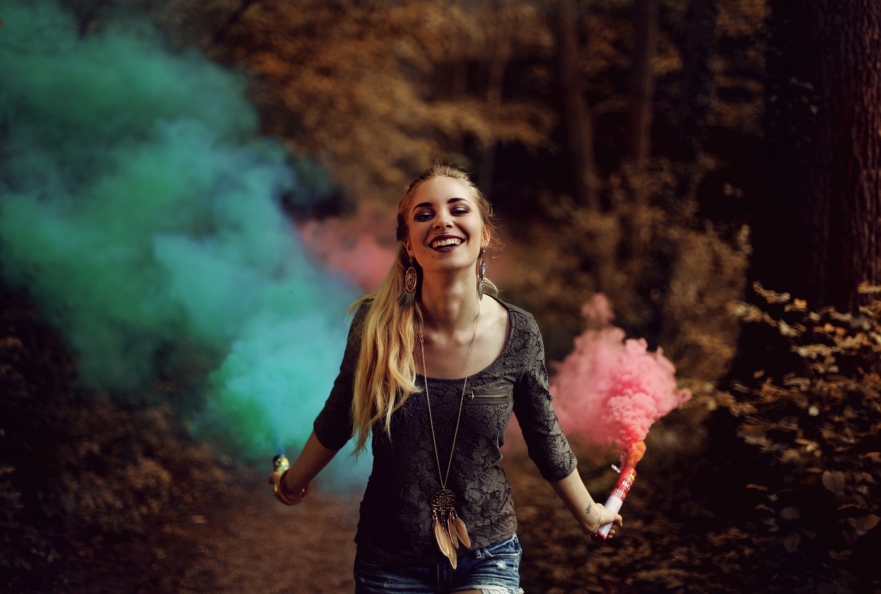 a woman holding a pink and green smoke bomb, a picture, tumblr, happy colors dariusz zawadzki, girl walking in dark forest, lovely smile, muted blue and red tones