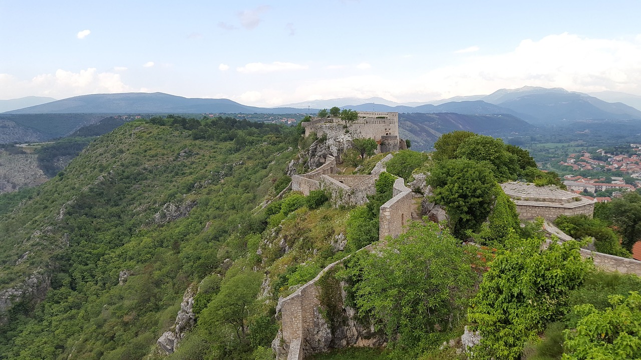 a castle sitting on top of a lush green hillside, by Adam Szentpétery, les nabis, taras susak, city wall, rosalia vila i tobella, view from the top