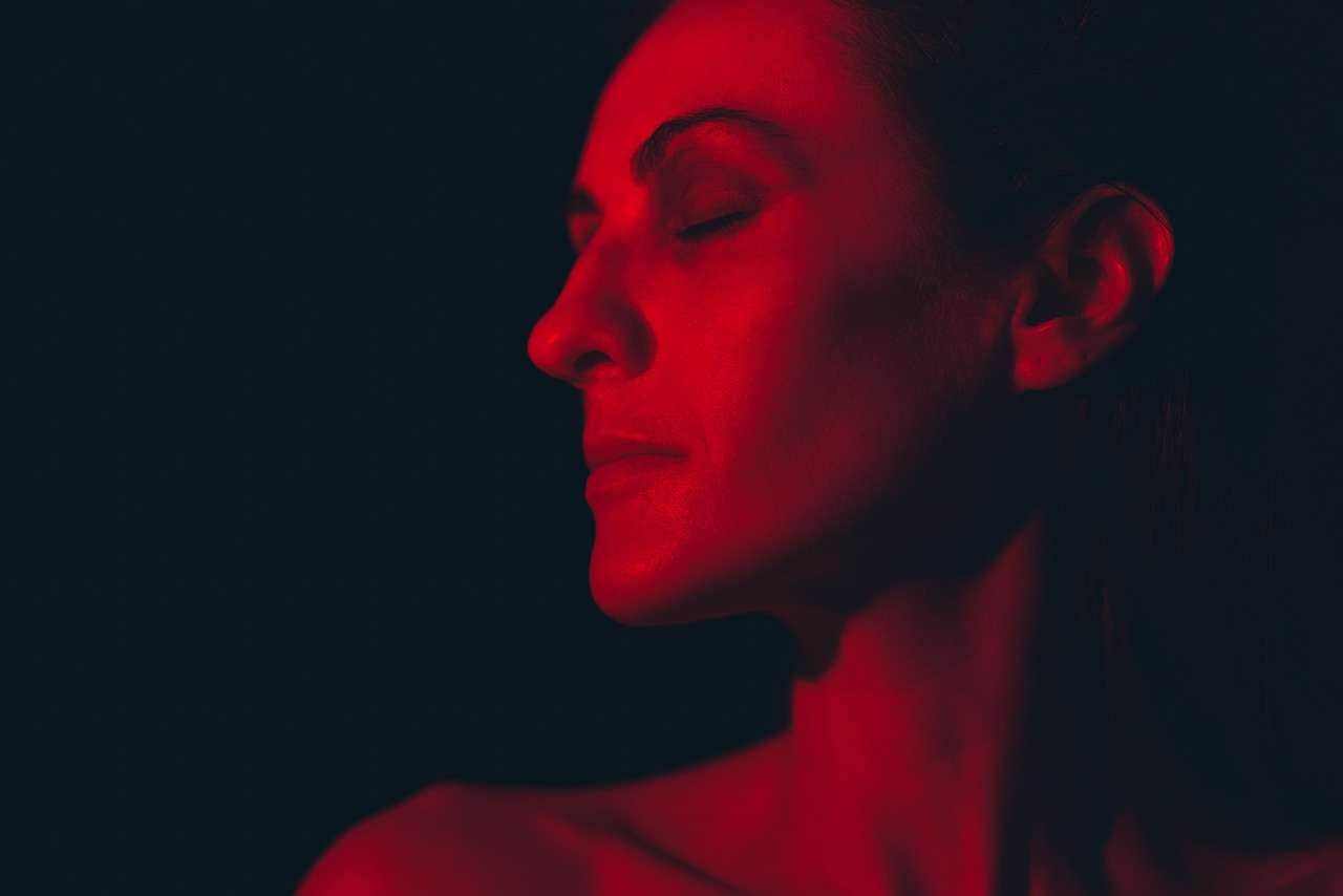 a woman with her eyes closed in a red light, a portrait, figuration libre, claudia black, color graded, volumetric lighting. red, shot from below