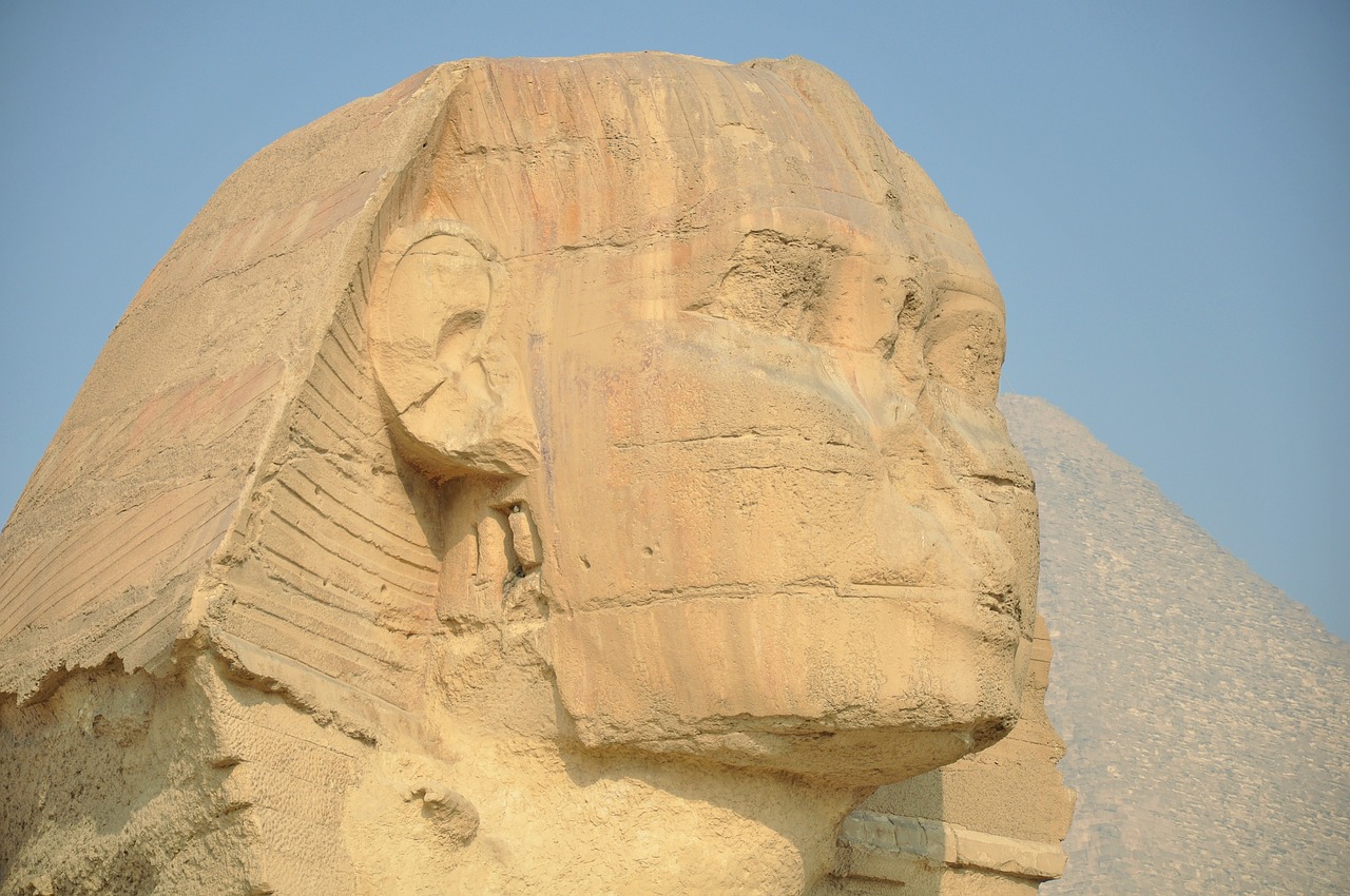 a close up of a statue in front of a pyramid, egyptian art, big sharp rock, gorgeous and huge head ornaments, side view of a gaunt, sandstone