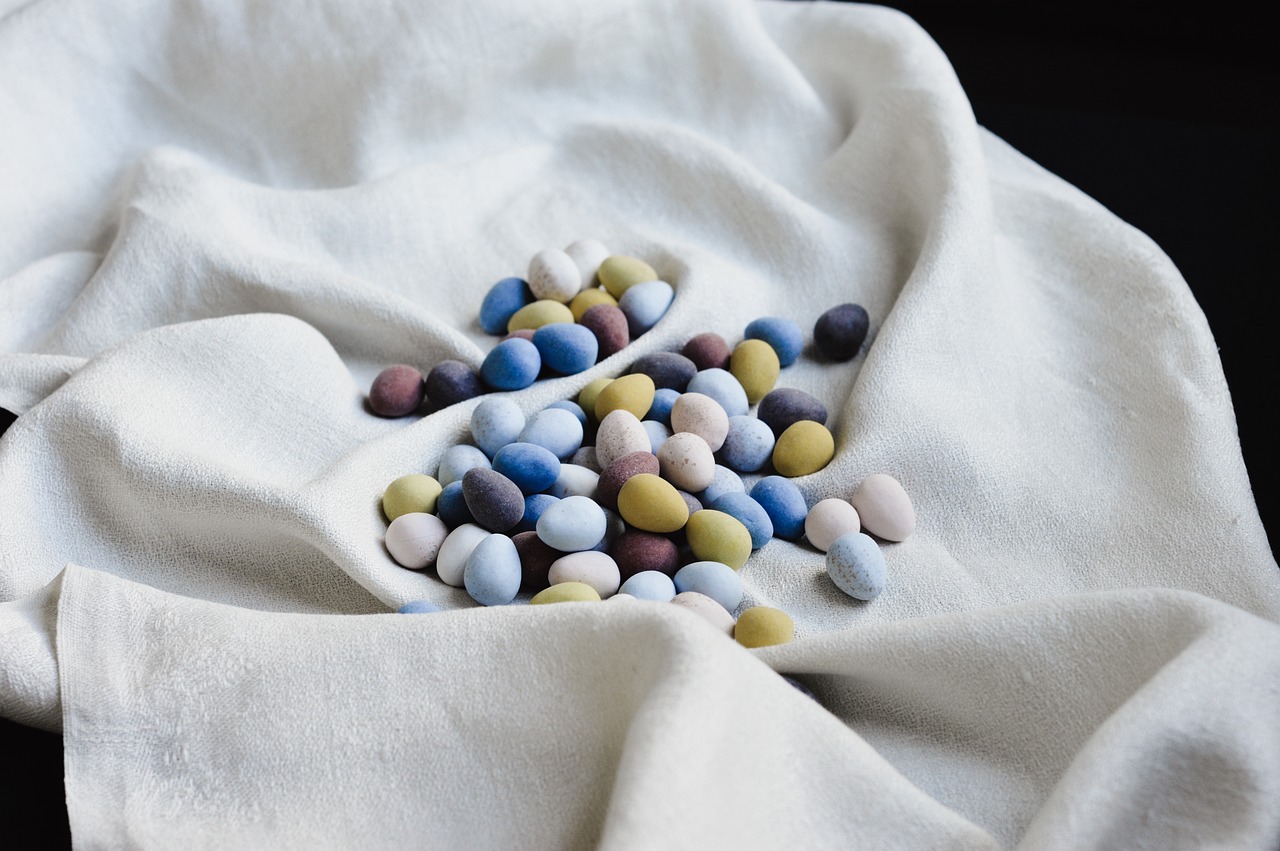 a pile of candy sitting on top of a white cloth, a pastel, by Anita Malfatti, beans, organic color, easter, scandinavian