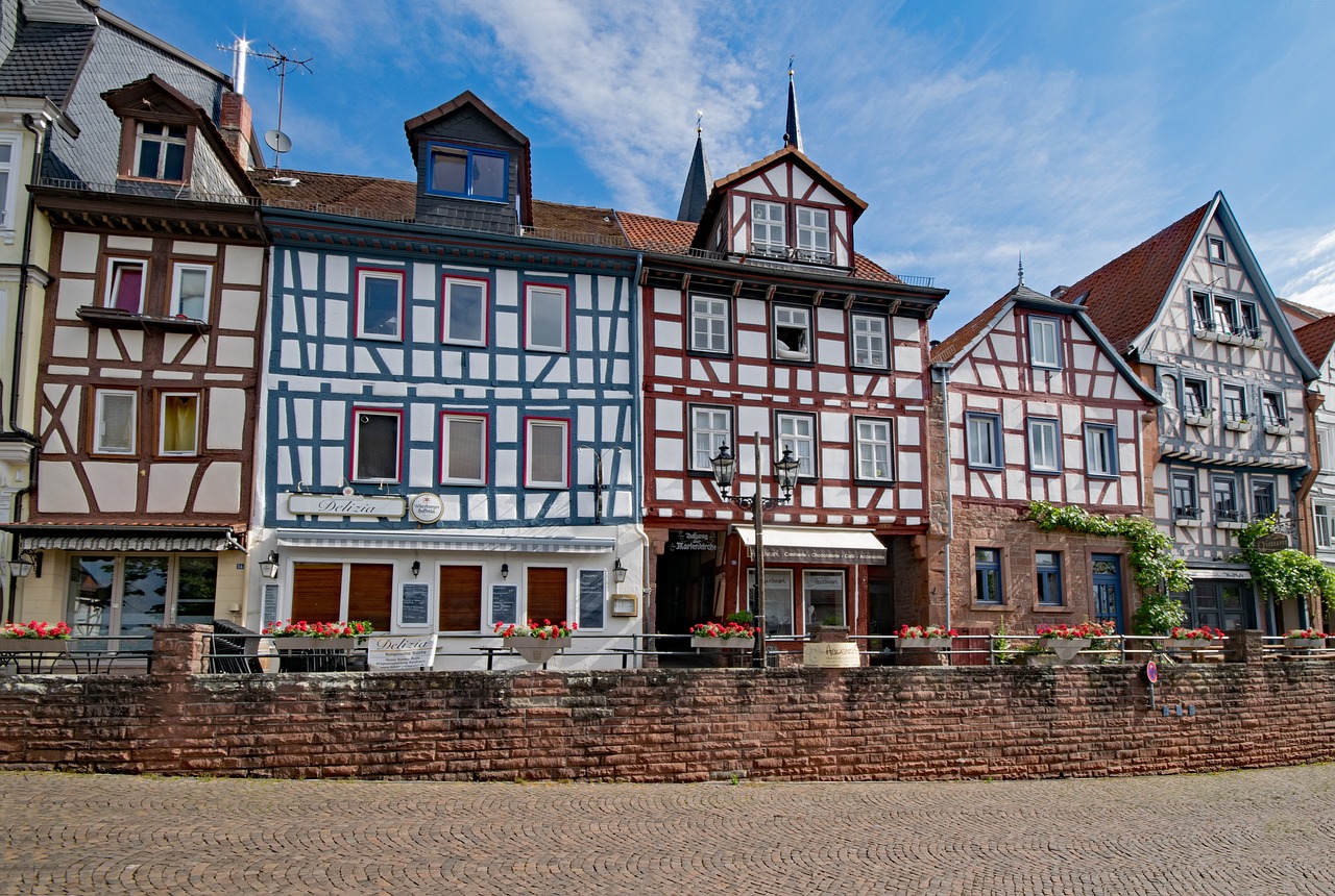 a row of buildings next to a brick wall, a photo, by Karl Hagedorn, shutterstock, heidelberg school, timbered house with bricks, 2 4 mm iso 8 0 0, stock photo, red castle in background