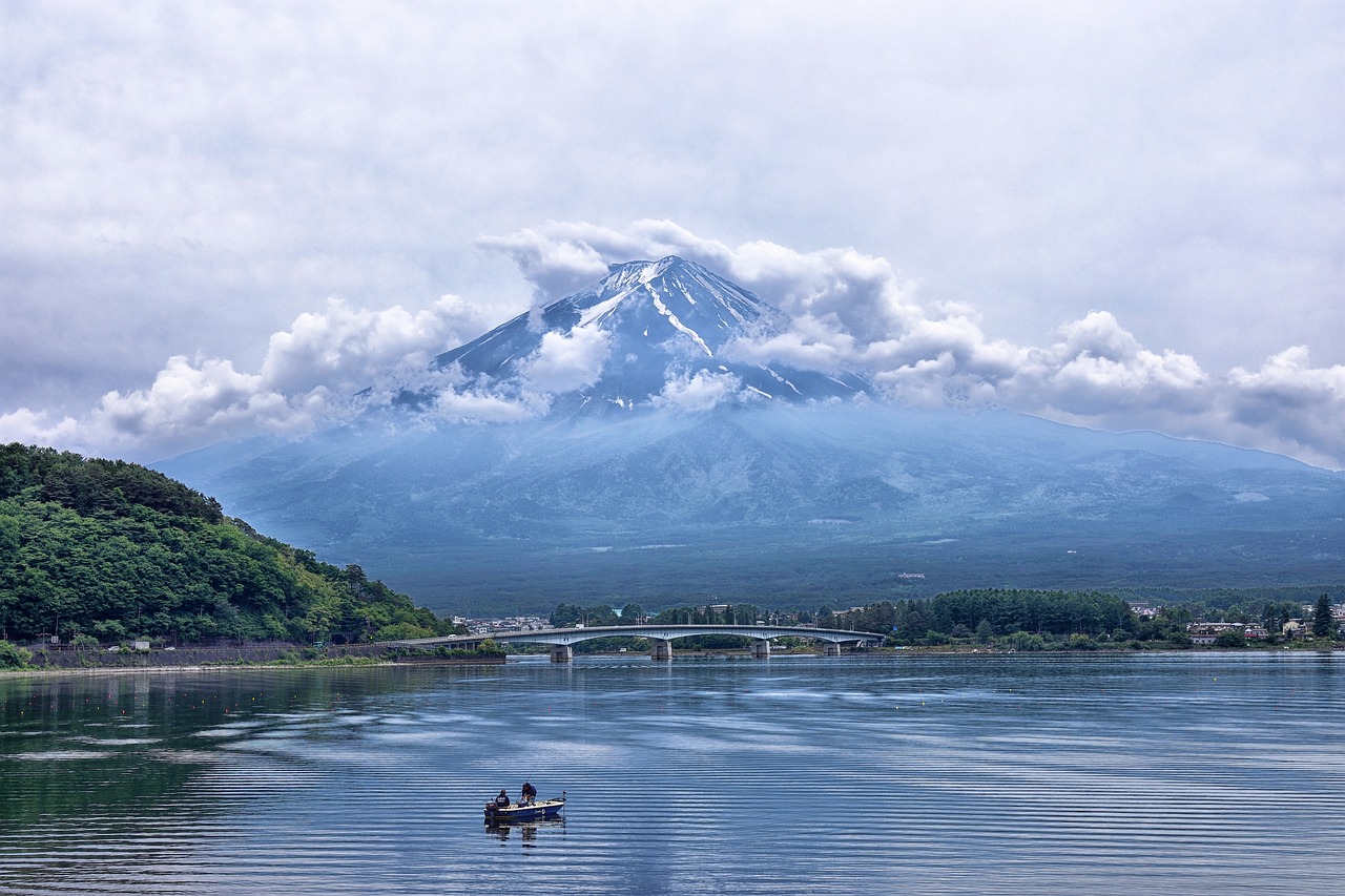 a boat in a body of water with a mountain in the background, a picture, shutterstock, sōsaku hanga, fuji lut, on a cloudy day, fisherman, summer