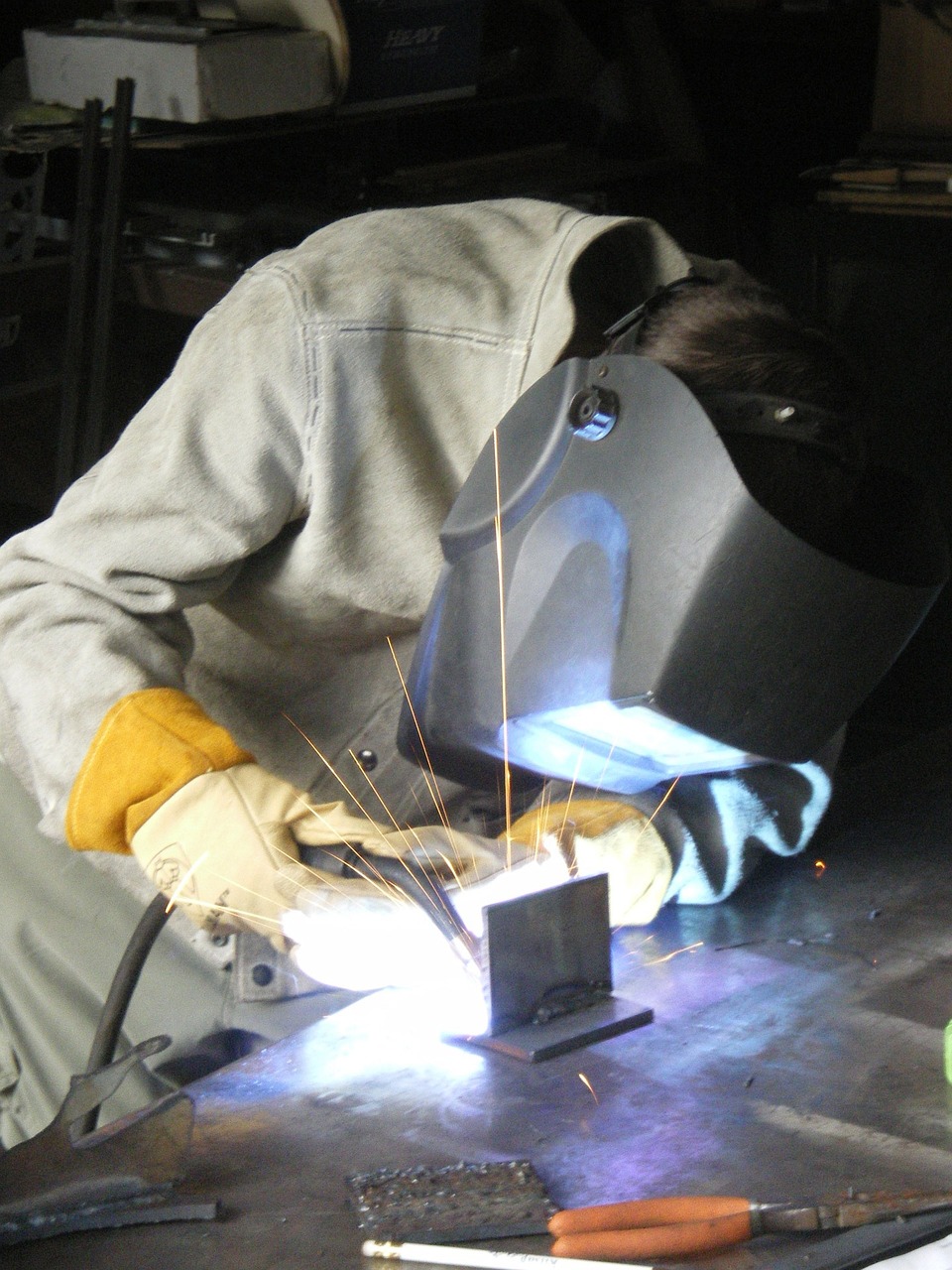 a man welding a piece of metal on a table, flickr, sleek metal ears, 2 0 1 0 photo, high school, wip