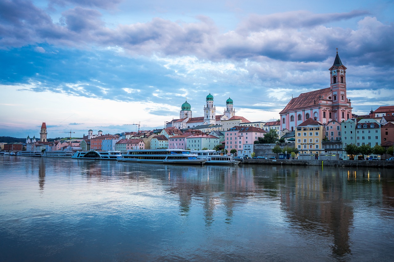 a large body of water with a city in the background, a photo, by Jakob Gauermann, shutterstock, art deco, austria, church, calm evening, building along a river