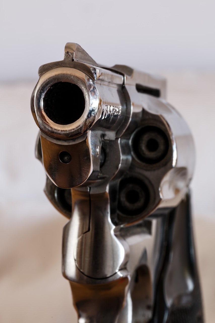 a silver revolver sitting on top of a wooden table, a macro photograph, pexels, bauhaus, headshot profile picture, violent action, white muzzle and underside, low - angle shot from behind