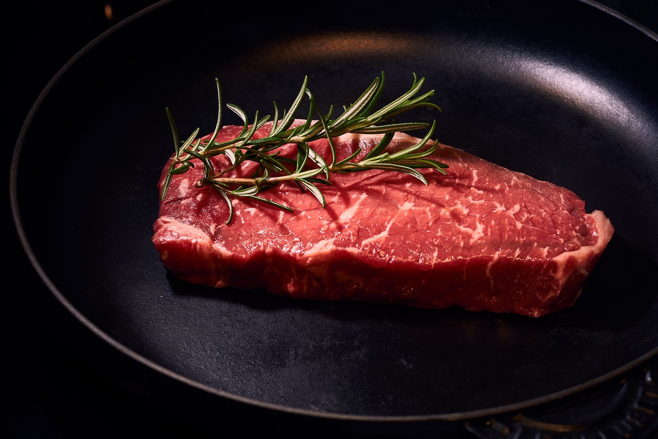 a steak on a black plate with a sprig of rosemary, a picture, by Alexander Robertson, shutterstock, realism, looking from side, usa-sep 20, photo taken in 2 0 2 0, stock photo