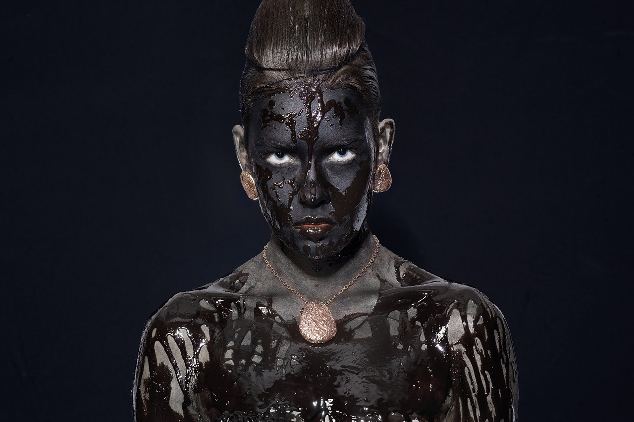 a close up of a person with black paint on their body, inspired by Martin Schoeller, ancient libu young girl, chocolate, menacing pose, awarded winning photo