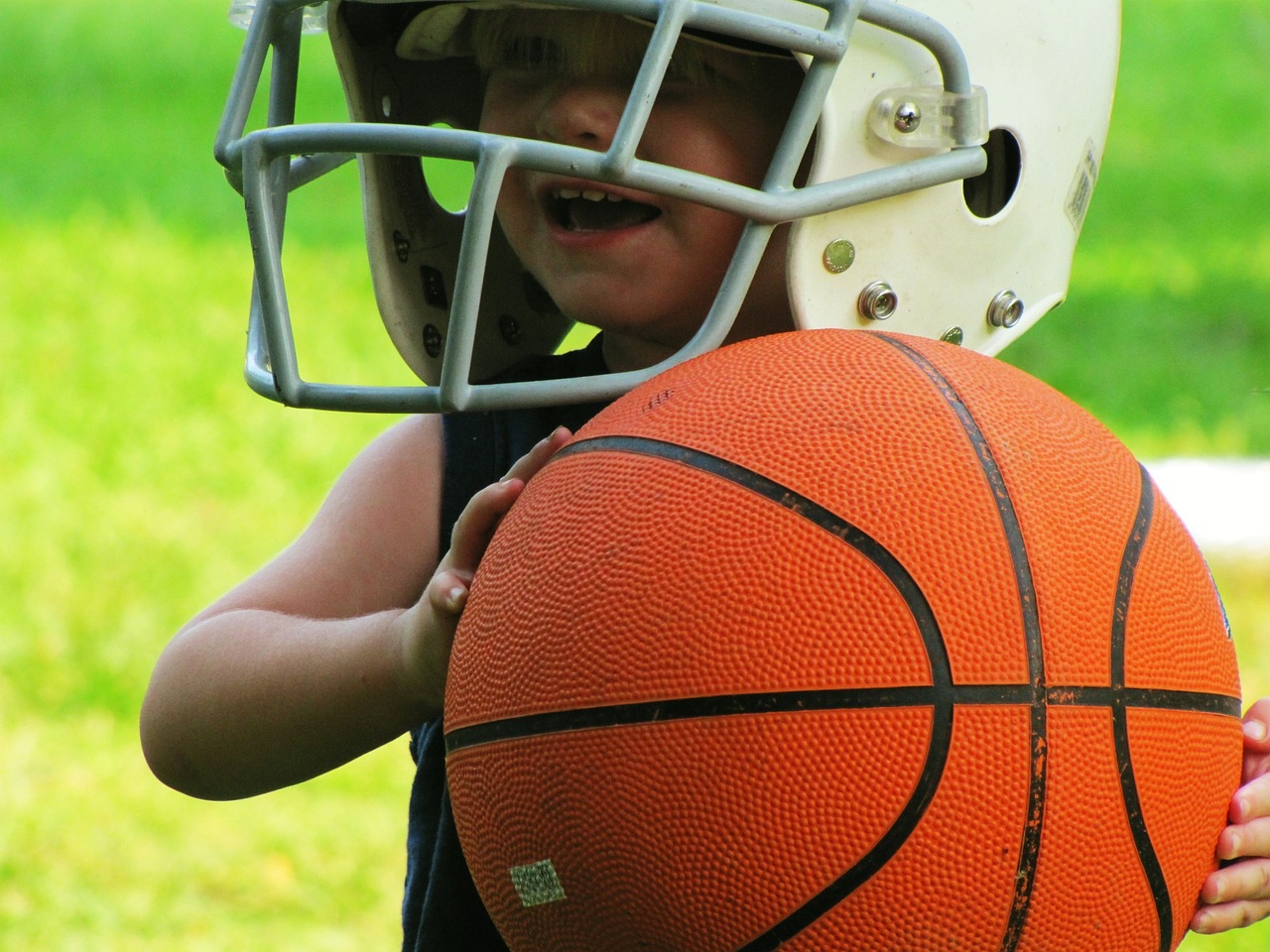 a young boy in a helmet holding a basketball, by James Warhola, dribble contest winner, istockphoto, football, toddler, 3 4 5 3 1