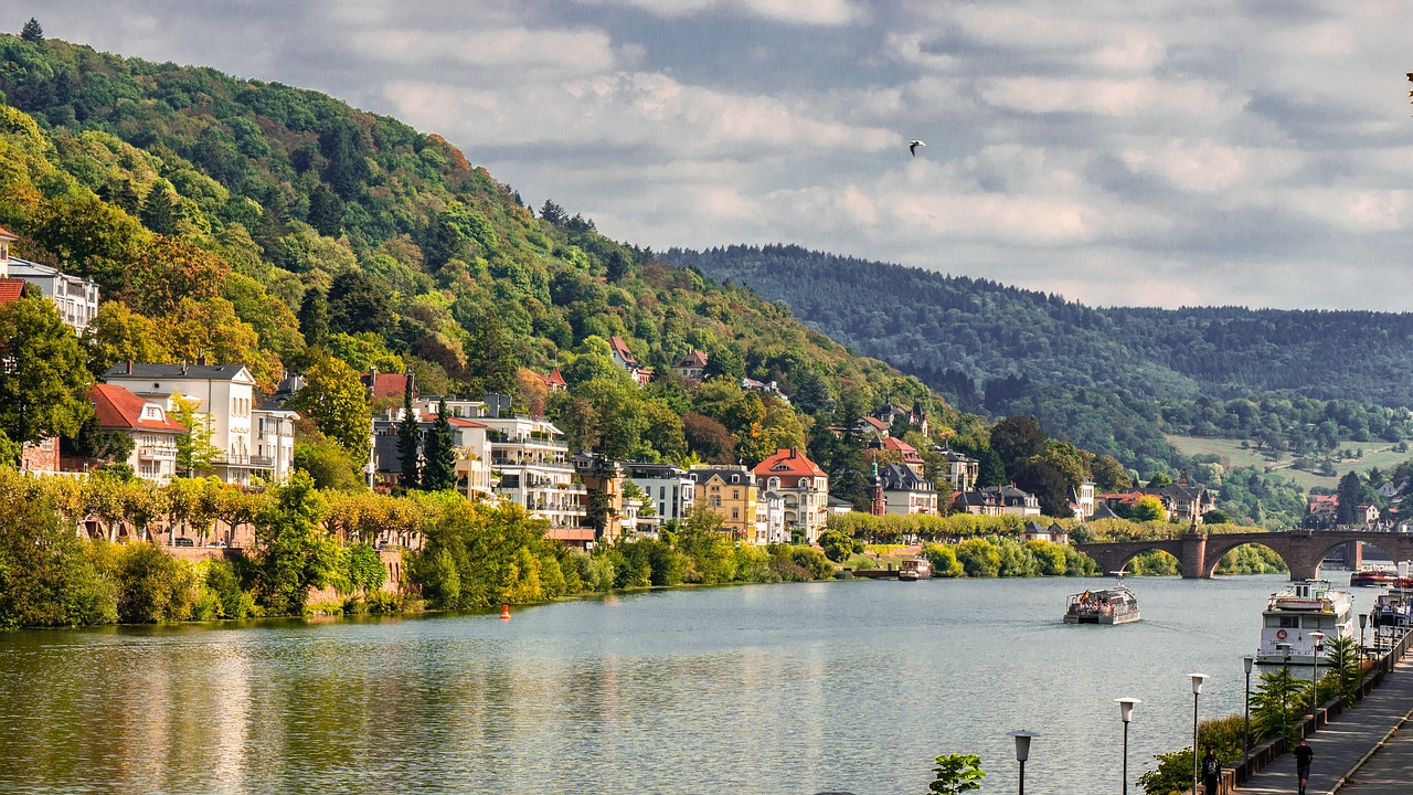 a river running through a lush green hillside, a photo, by Emanuel Büchel, shutterstock, art nouveau, waterfront houses, germany. wide shot, on a lake, city panorama