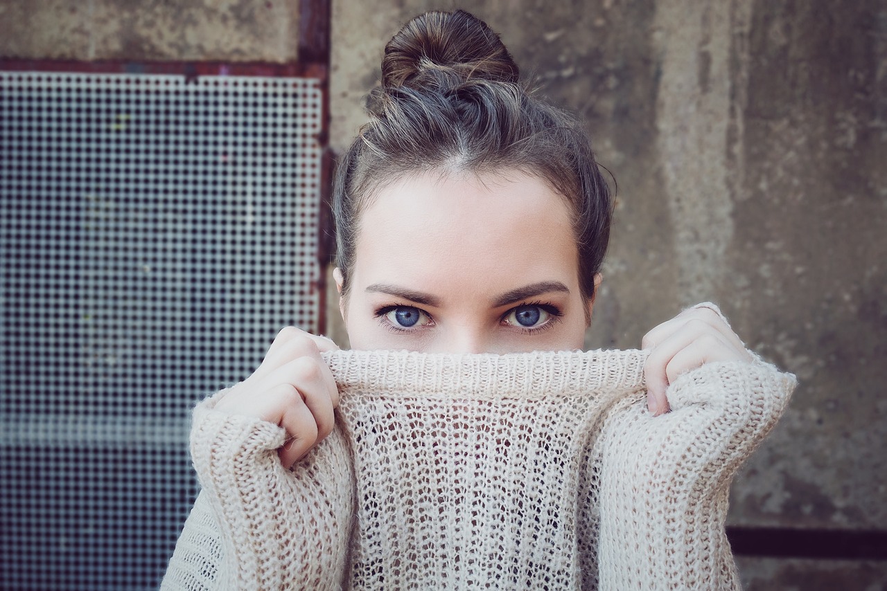 a woman hiding her face behind a sweater, a picture, perfect blue eyes, topknot, vintage color, beautiful confident eyes