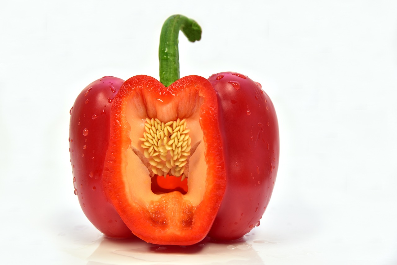 a red bell pepper cut in half on a white surface, a picture, nature photo, supersharp photo, mid shot photo