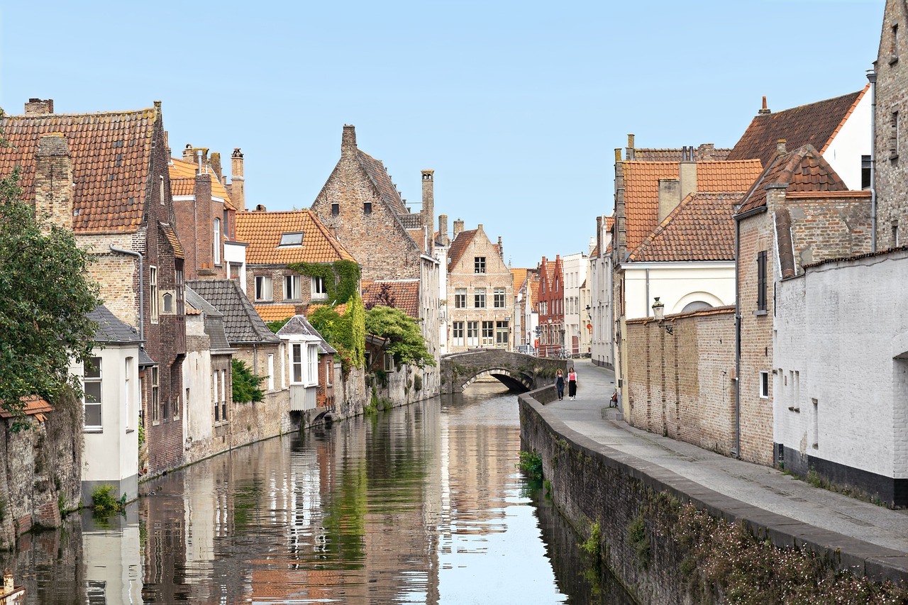 a river running through a small town next to tall buildings, a photo, by Jacob Esselens, shutterstock, renaissance, flanders, buttresses, serene scene, all buildings on bridge