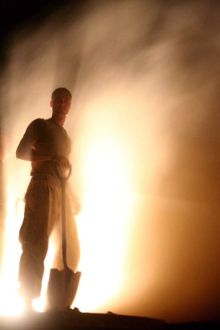 a man standing in front of a fire with a shovel, flickr, hurufiyya, theatrical lighting, mist, kanye, ultrafine detail ”