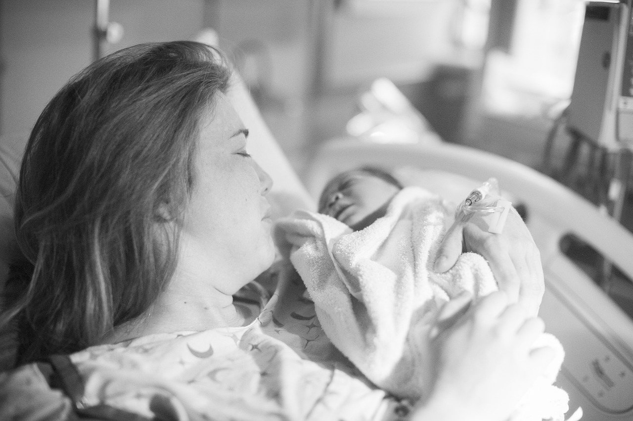 a woman holding a baby in a hospital bed, a black and white photo, by Dan Frazier, pexels, fine art, brittney lee, morning glow, grand finale, close together