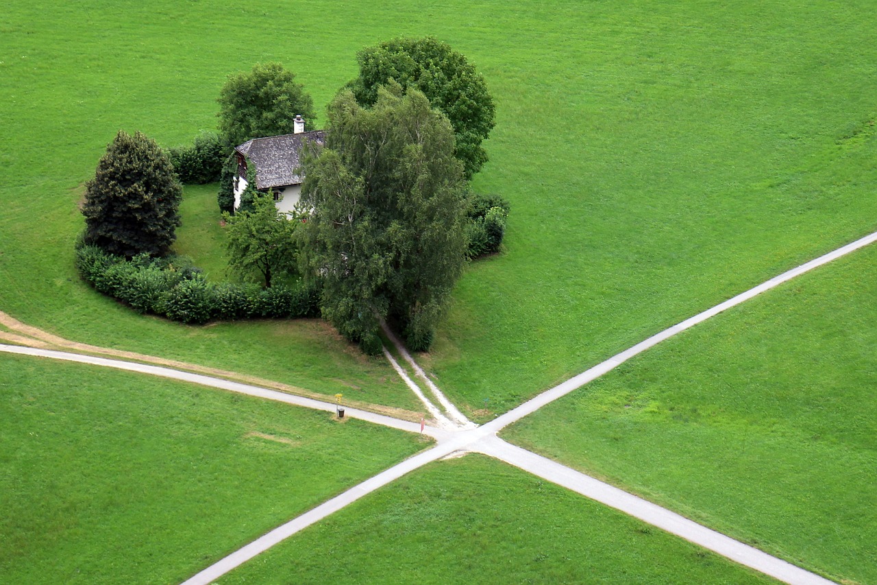 a small house sitting on top of a lush green field, by Hans Schwarz, land art, intersection, pathway, cross haching, movie set”