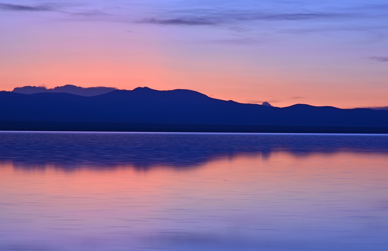 a large body of water with mountains in the background, by Andrei Kolkoutine, shutterstock, minimalism, colorful sunset, new hampshire, albuquerque, smooth reflections